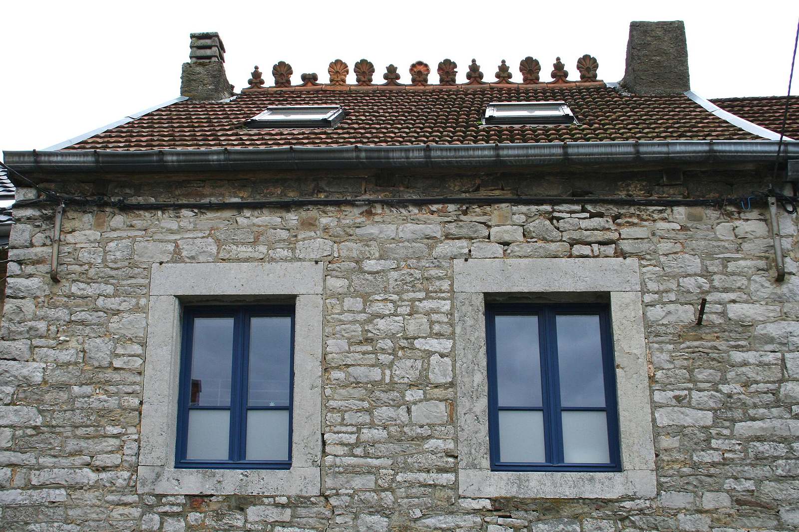 Stenen woning met een pannendak, versierde nokpannen en dakramen